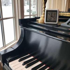 Image of black grand piano with humidity monitor