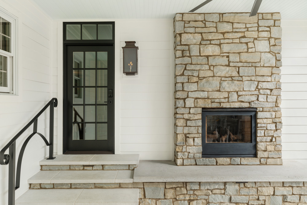 black single french exterior door with transom next to a stone fireplace